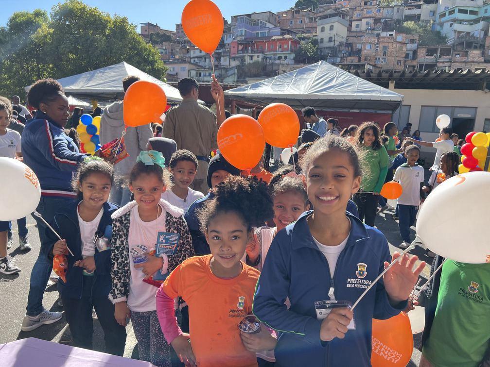 Crianças sorrindo com balões em ação de conscientização em escola